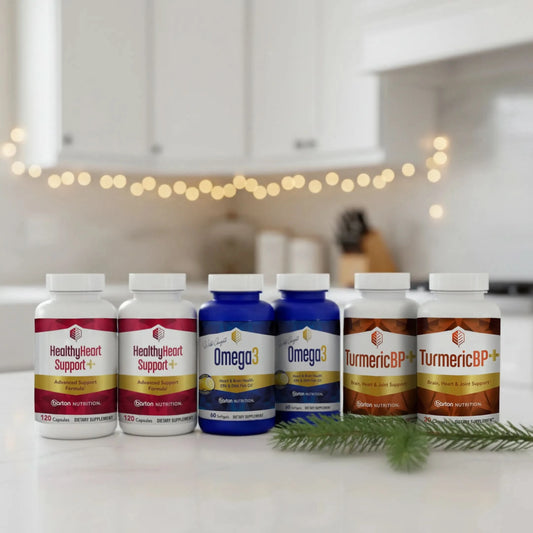 HealthyHeart Support+, Omega3 and TurmericBP+ bottles on a kitchen counter with decorative lights in the background